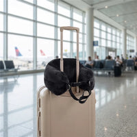 Black | Fillable Washable U-Shaped Travel Pillow, attached to a suitcase handle at the airport