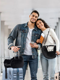 Black | Fillable Washable U-Shaped Travel Pillow, couple at the airport, pillow on the shoulder strap and on the suitcase