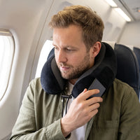 Black | U-Shaped Memory Foam Airplane Neck Pillow, man holding a phone by the pillow pocket on a plane