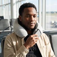 Grey | U-Shaped Memory Foam Airplane Neck Pillow, man holding a phone by the pillow pocket